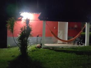 a red building with a hammock in front of it at night at Pousada do Tie - Rio Preto MG in São José do Rio Preto