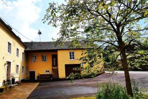 um edifício amarelo com uma árvore em frente em Bruce's Countryhouse em Niederweis