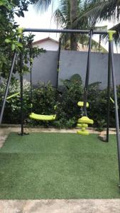 un parque infantil con columpios amarillos y césped verde en Inviting 3-Bed Apartment in Kumasi Ashanti Ghana, en Dompoasi