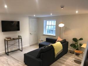 a living room with a black couch and a tv at Apartment 1 St Georges in Cheltenham