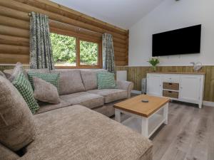 ein Wohnzimmer mit einem Sofa und einem Flachbild-TV in der Unterkunft Redwood Lodge in Ellesmere