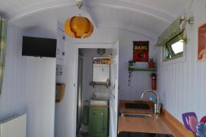 a small kitchen with a sink and a refrigerator at Twin Barn Shepherd’s Huts in Norwich
