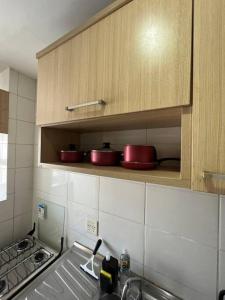 una cucina con pentole e padelle rosse su uno scaffale di Belo Apartamento em Condomínio ad Ananindeua