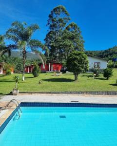 a swimming pool in front of a house with a yard at Pousada do Tie - Rio Preto MG in São José do Rio Preto