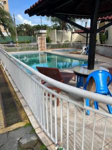 a swimming pool with a white fence and two chairs at Belo Apartamento em Condomínio in Ananindeua