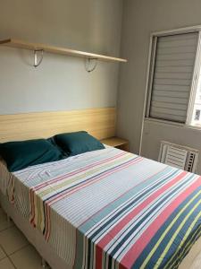 een slaapkamer met een groot bed en een gestreepte deken bij Belo Apartamento em Condomínio in Ananindeua