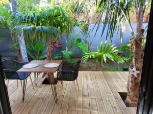 einen Holztisch und Stühle auf einer Terrasse mit einem Teich in der Unterkunft Tiny house au lagon in Saint-Paul