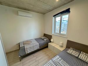 - 2 lits dans une chambre avec fenêtre dans l'établissement Heart of the Paceville Modern Apartment!, à San Ġiljan