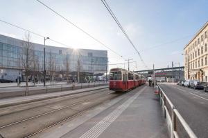 un tren rojo en las vías de una ciudad en Cozy Apartment in Quiet Location, Fast Train Station 100m Away, contactless check-in, en Viena
