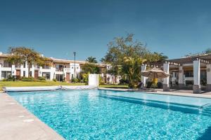 a blue swimming pool with an umbrella and some buildings at Villa Exclusiva en Cuernavaca: Casa con Alberca in Xochitepec