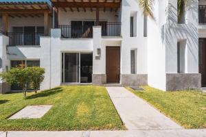 a white house with a door and a grass yard at Villa Exclusiva en Cuernavaca: Casa con Alberca in Xochitepec