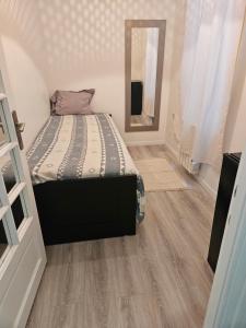 a small bedroom with a bed and a mirror at appartement 93 proche stade de France in Saint-Denis