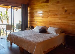 1 dormitorio con 1 cama con pared de madera en San José del Pacífico Camino al Cielo, en El Pacífico