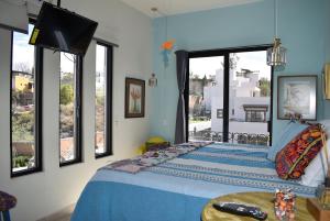 a bedroom with a bed with blue sheets and windows at Casa Itzae La Antigua Dog Friendly in San Miguel de Allende