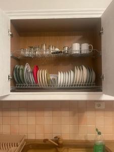 une étagère avec des assiettes, des casseroles et des poêles dans une cuisine dans l'établissement Уютная квартира на берегу Адриатического моря, à Durrës