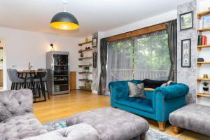 切爾滕納姆的住宿－The Coach House，客厅配有蓝色的沙发和椅子