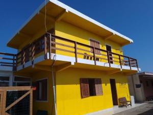 ein gelbes Haus mit Balkon darüber in der Unterkunft Pousada do Osvaldo Imbé in Imbé