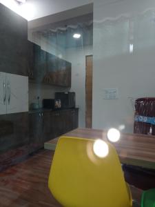 Namoh hotels في غازي آباد: كرسي اصفر في غرفة مع مطبخ