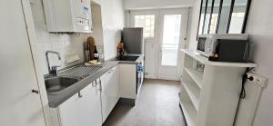 a white kitchen with a sink and a microwave at CoeurDeSable - Appartement T3 Hyper Centre Arcachon - Parking in Arcachon