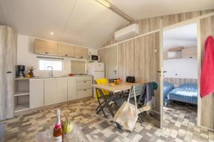 eine Küche mit einem Tisch und Stühlen im Zimmer in der Unterkunft Mobilhome 5 étoiles - Parc aquatique - eeiadg in Brem Sur Mer