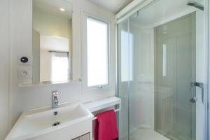 ein weißes Bad mit einem Waschbecken und einer Dusche in der Unterkunft Mobilhome 5 étoiles - Parc aquatique - eeiadg in Brem Sur Mer