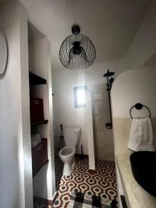 a small bathroom with a toilet and a chandelier at Le Cabaoui in Poponguine