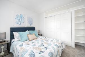 a bedroom with a bed with a blue and white bedspread at 2 Bedroom steps to the beach in West Newport in Newport Beach