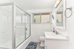 uma casa de banho com um chuveiro, um lavatório e um WC. em West Newport Duplex on the Sand with Patio-Sleeps 12 em Newport Beach
