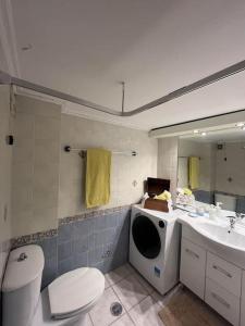 y baño con aseo, lavabo y lavadora. en Maria's Sunlit Apartment, en Pireo