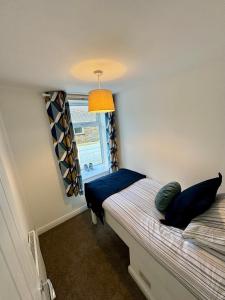 a bedroom with a bed with blue pillows and a window at Spacious home near park and playing fields in Aberdare