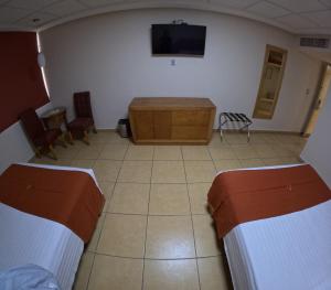 Habitación con 2 camas, mesa y TV. en Hotel Yvette en León