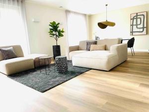 una sala de estar con 2 sofás blancos y una alfombra en New Apartment In City Centre Large, en Oirschot