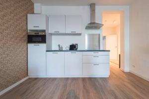 a kitchen with white appliances and a wooden floor at Spacious Apartment Lana, Clean Comfy in Tilburg