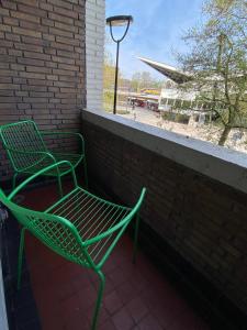 2 chaises vertes assises à côté d'un mur de briques dans l'établissement Modern Studio In Tilburg Kitchen & Bathroom, à Tilbourg