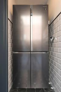 een roestvrijstalen koelkast in een keuken met een bakstenen muur bij Room In The Center Of Tilburg Low Budget in Tilburg