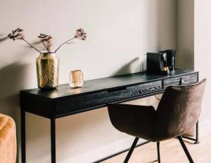 einen schwarzen Schreibtisch mit einem Stuhl und eine Vase mit Blumen in der Unterkunft Apartment With Bath, Kitchen, Garden Stadsvilla in Tilburg