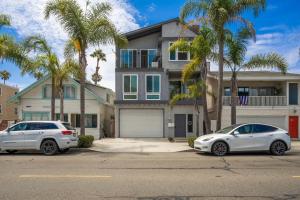 dois carros estacionados em frente a uma casa com palmeiras em 6 Bedroom Duplex near the Balboa Pier and Fun Zone with AC em Newport Beach