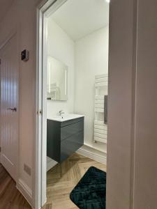 a bathroom with a sink and a mirror at Spacious home near park and playing fields in Aberdare