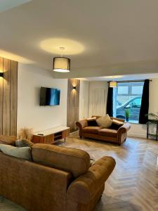 a living room with two couches and a table at Spacious home near park and playing fields in Aberdare