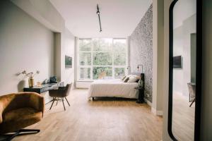 a bedroom with a bed and a large window at Luxe Suite With Garden And Bath Sophie in Tilburg