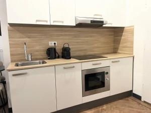 a white kitchen with a sink and a microwave at Cozy Studio Unit With Kitchen & Bathroom in Tilburg