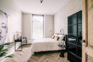 a white bedroom with a bed and a window at Large Apartment With 2 Bedrooms Stadsvilla in Tilburg
