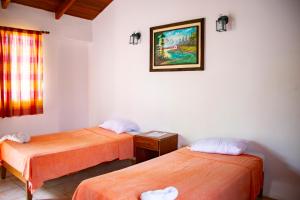 een kamer met twee bedden en een foto aan de muur bij VÉLEZ Beach Hotel in San Juan del Sur
