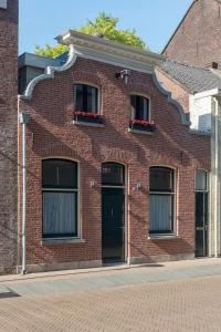 ein rotes Backsteingebäude mit zwei Fenstern und einer Tür in der Unterkunft Cozy Suite With New Shower Near Popodium 013 in Tilburg