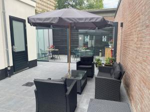 un patio con sombrilla, sillas y mesa en Lovely Suite Newly Renovated en Tilburg