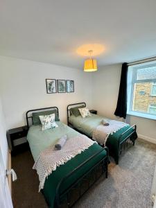 1 dormitorio con 2 camas y ventana en Spacious home near park and playing fields, en Aberdare