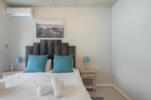 a bedroom with a large white bed with blue pillows at 105 On KOI by Host Agents in Ballito +15 photos