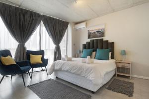 a bedroom with a large bed with blue and yellow pillows at 105 On KOI by Host Agents in Ballito