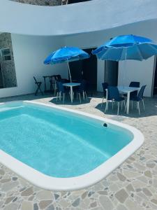 a swimming pool with umbrellas and tables and chairs at Atena Flats in Aracaju