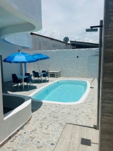a swimming pool with blue umbrellas and a table and chairs at Atena Flats in Aracaju